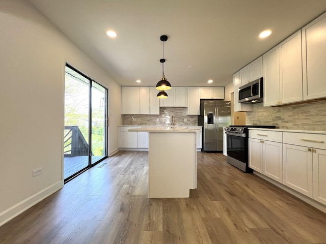 kitchen with stainless steel appliances, decorative backsplash, wood finished floors, white cabinets, and a kitchen island