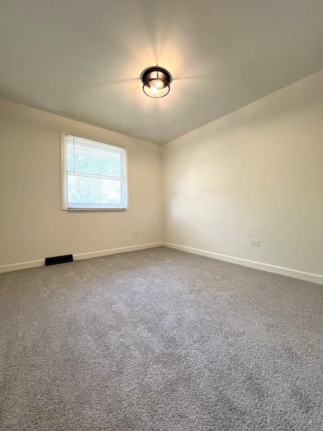 carpeted empty room featuring baseboards