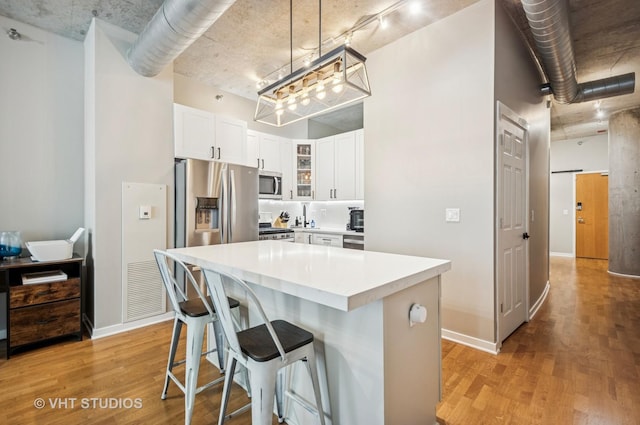 700 N Larrabee St Unit 905, Chicago, IL 60654 - kitchen with appliances with stainless steel finishes, light wood finished floors, glass insert cabinets, and a kitchen bar