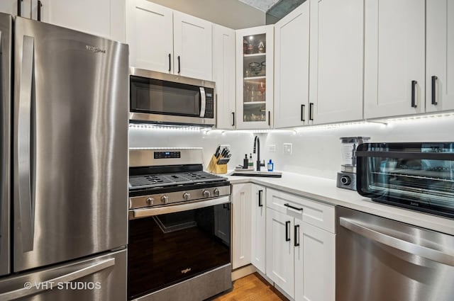 700 N Larrabee St Unit 905, Chicago, IL 60654 - kitchen featuring appliances with stainless steel finishes, light countertops, glass insert cabinets, and white cabinetry