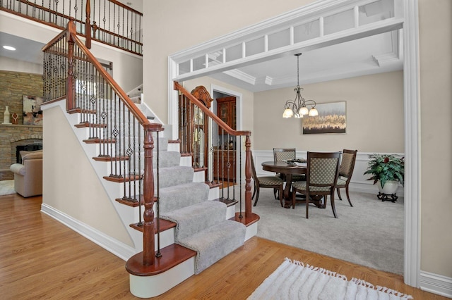 1021 Fire Fox Ct, Saint Charles, IL 60174 - stairs with a chandelier, a fireplace, a high ceiling, wood finished floors, and wainscoting