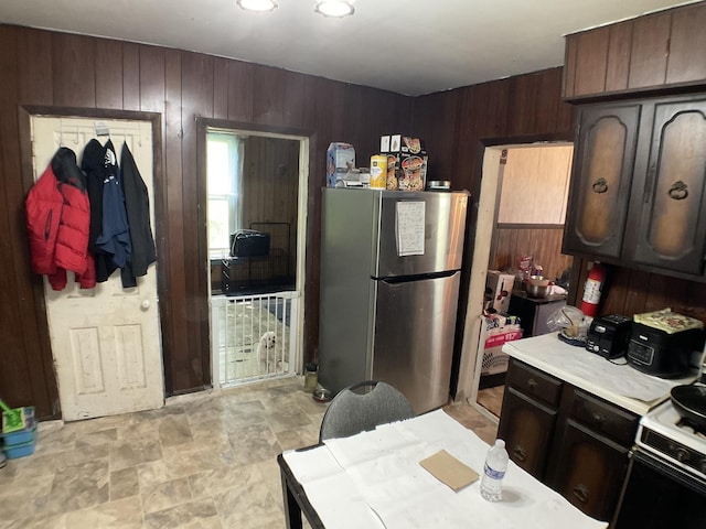 207 W Williams St, Dwight, IL 60420 - kitchen featuring freestanding refrigerator, light countertops, wooden walls, gas stove, and stone finish flooring