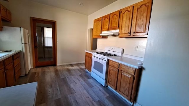 443 E St, Depue, IL 61322 - kitchen featuring white appliances, under cabinet range hood, dark wood-style floors, brown cabinetry, and light countertops