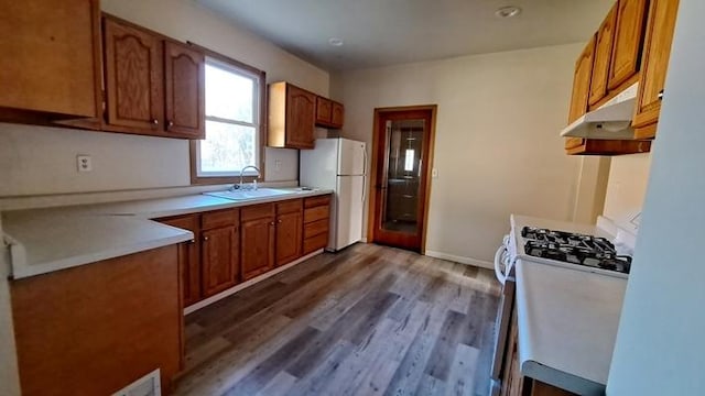 443 E St, Depue, IL 61322 - kitchen with under cabinet range hood, white appliances, a sink, wood finished floors, and brown cabinets