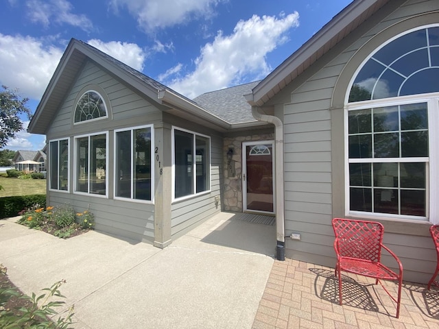 2018 Olmstead Dr Unit 2018, Woodstock, IL 60098 - back of house featuring a patio, roof with shingles, and stone siding