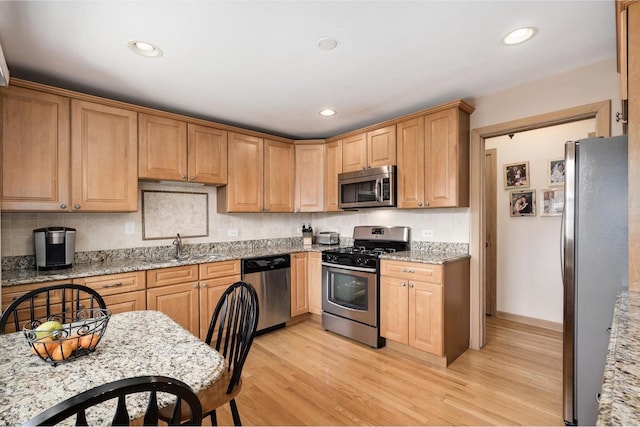 4522 N Reserve Ave, Chicago, IL 60656 - kitchen featuring stainless steel appliances, a sink, light wood-type flooring, light stone counters, and tasteful backsplash