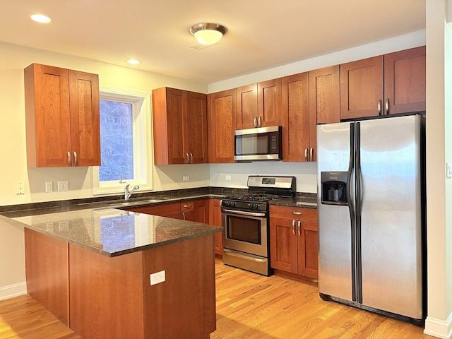 25 E 26th St Unit 2, Chicago, IL 60616 - kitchen with appliances with stainless steel finishes, a peninsula, a sink, light wood-style floors, and dark stone countertops