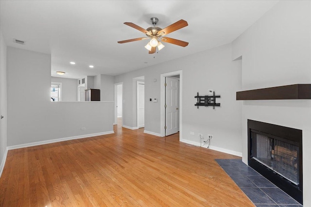 unfurnished living room with a fireplace with flush hearth, a ceiling fan, wood finished floors, baseboards, and recessed lighting