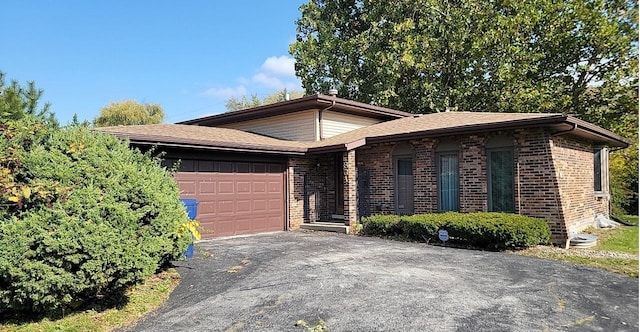 view of front of property featuring asphalt driveway, a garage, and brick siding