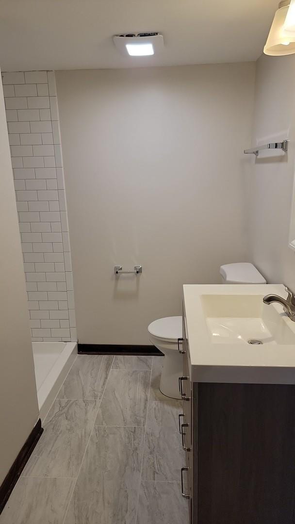 full bath featuring vanity, toilet, baseboards, and a stall shower