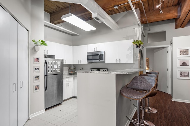 225 W Huron St Unit 402, Chicago, IL 60654 - kitchen featuring appliances with stainless steel finishes, a breakfast bar area, white cabinets, and wooden ceiling