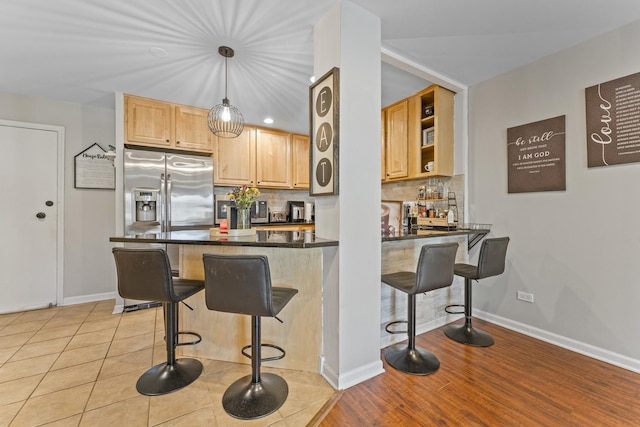310 Lathrop Ave Unit 202-204, Forest Park, IL 60130 - kitchen featuring stainless steel refrigerator with ice dispenser, dark countertops, a breakfast bar area, tasteful backsplash, and light brown cabinets