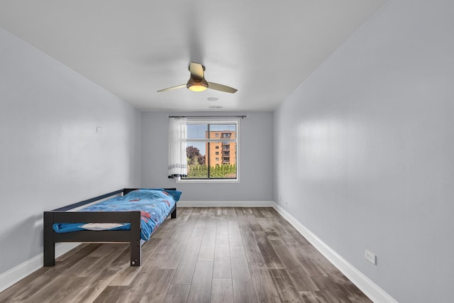 bedroom with wood finished floors, baseboards, and ceiling fan