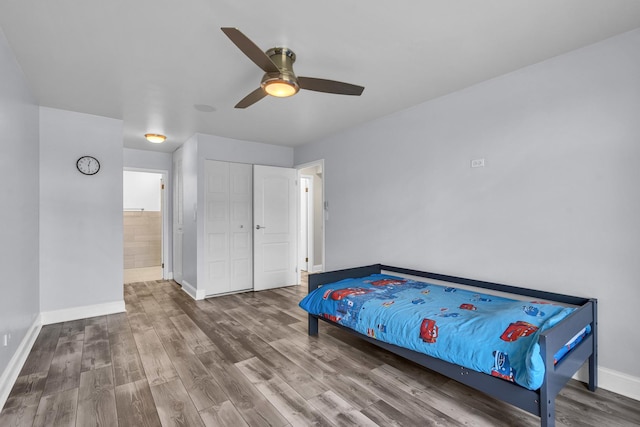 bedroom featuring baseboards, wood finished floors, ceiling fan, and a closet