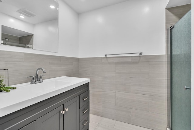bathroom featuring tiled shower, vanity, tile walls, and recessed lighting