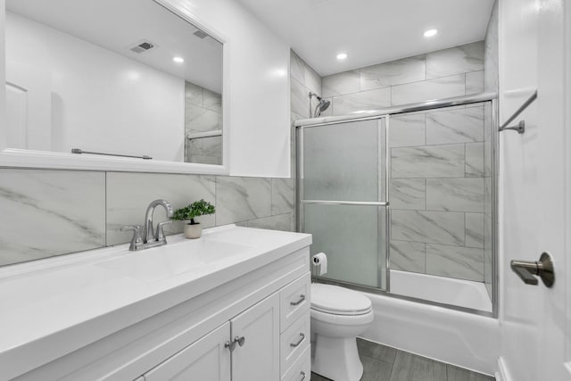 full bath with shower / bath combination with glass door, toilet, vanity, tile walls, and recessed lighting