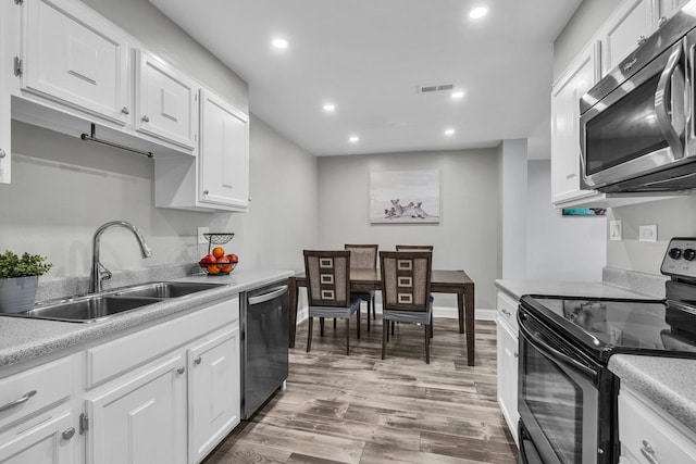 kitchen with appliances with stainless steel finishes, a sink, recessed lighting, light countertops, and white cabinets