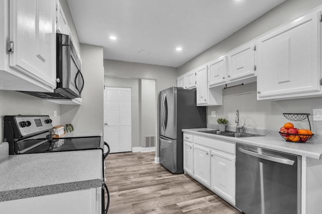 kitchen featuring stainless steel appliances, a sink, white cabinets, recessed lighting, and light countertops