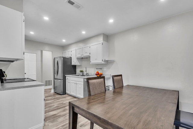 kitchen featuring freestanding refrigerator, stove, white cabinetry, light wood-style floors, and recessed lighting
