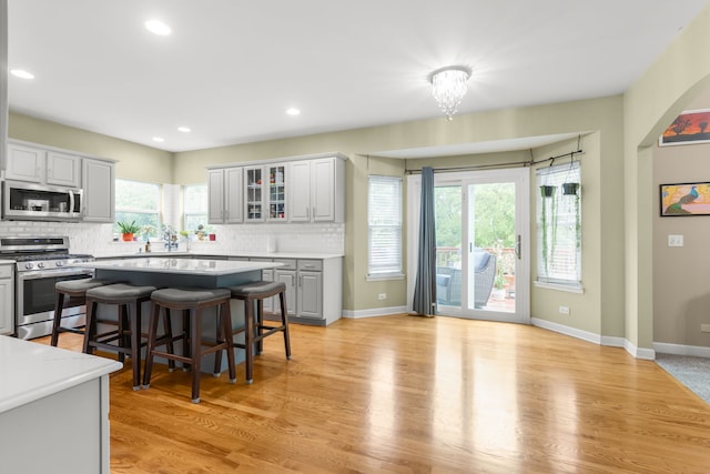 1984 Seaview Dr, Aurora, IL 60503 - kitchen with appliances with stainless steel finishes, backsplash, a breakfast bar, light countertops, and glass insert cabinets