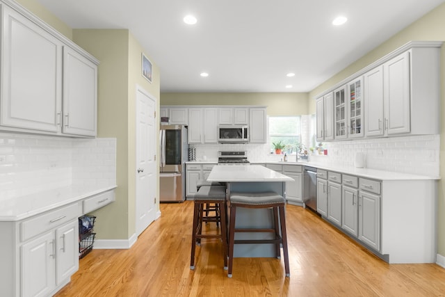 1984 Seaview Dr, Aurora, IL 60503 - kitchen with appliances with stainless steel finishes, a breakfast bar, tasteful backsplash, gray cabinets, and glass insert cabinets