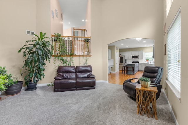 1984 Seaview Dr, Aurora, IL 60503 - living room featuring light carpet, a high ceiling, baseboards, arched walkways, and recessed lighting