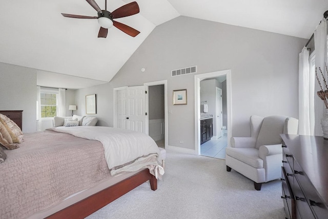 bedroom featuring high vaulted ceiling, light colored carpet, ensuite bath, ceiling fan, and baseboards