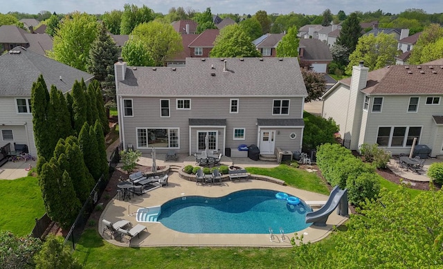 back of property with a residential view, a patio area, a chimney, and an outdoor pool