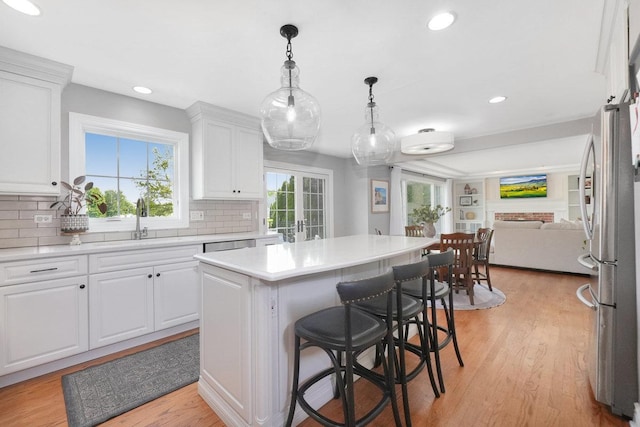 kitchen with a sink, white cabinets, open floor plan, a center island, and recessed lighting