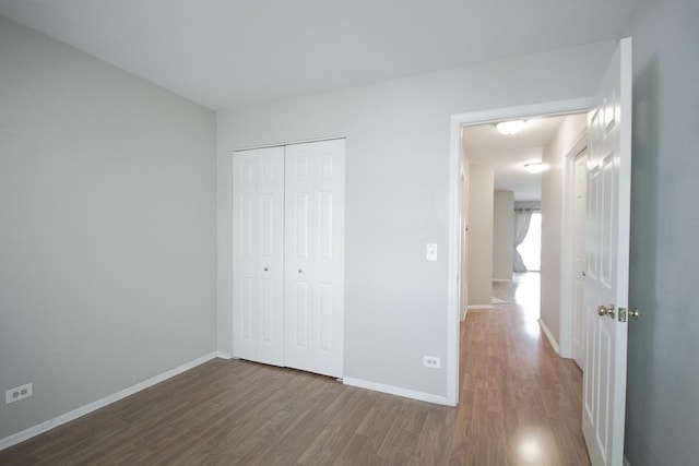 unfurnished bedroom with wood finished floors, a closet, and baseboards