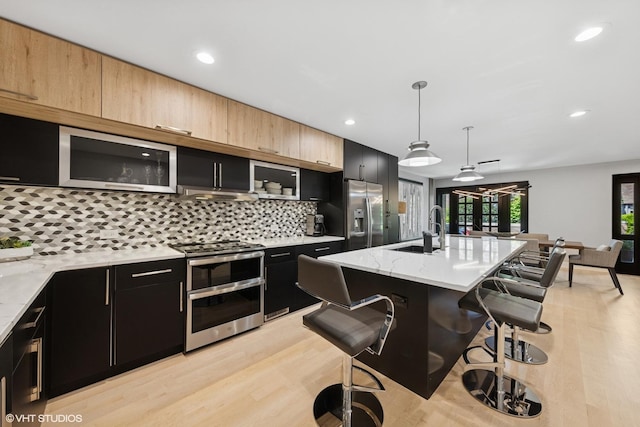 509 Burr Oak Pl, Hinsdale, IL 60521 - kitchen featuring appliances with stainless steel finishes, a sink, dark cabinets, a breakfast bar area, and backsplash
