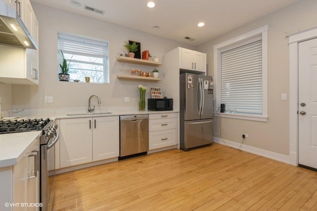 2151 W Cortez St, Chicago, IL 60622 - kitchen with appliances with stainless steel finishes, a sink, under cabinet range hood, light wood-style flooring, and white cabinetry