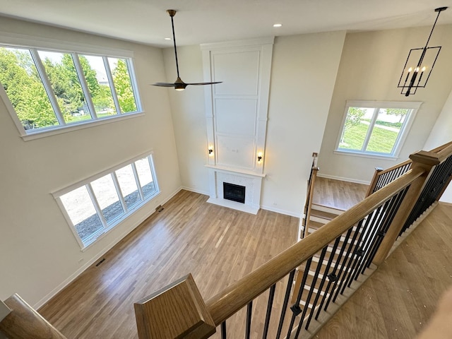 unfurnished living room featuring healthy amount of natural light, a fireplace with flush hearth, wood finished floors, baseboards, and recessed lighting