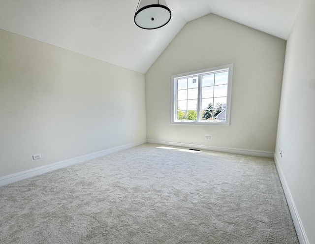 carpeted empty room featuring lofted ceiling and baseboards