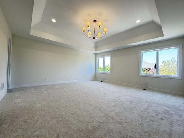 carpeted empty room with a tray ceiling, a chandelier, recessed lighting, and baseboards