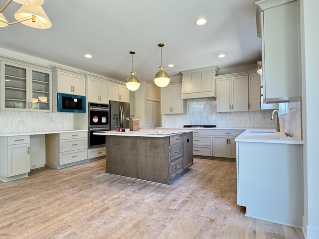 kitchen with stainless steel appliances, custom exhaust hood, tasteful backsplash, a kitchen island, and a sink