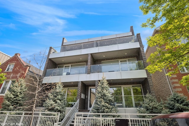 rear view of house with brick siding and a balcony