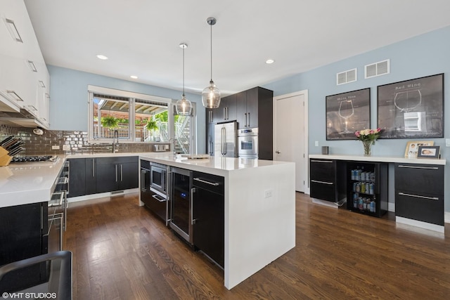 kitchen featuring dark cabinets, light countertops, appliances with stainless steel finishes, dark wood-style floors, and recessed lighting