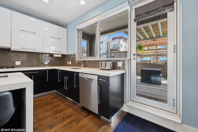 kitchen with stainless steel dishwasher, a sink, dark cabinetry, light countertops, and white cabinetry