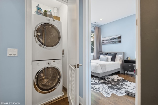 washroom with stacked washer / drying machine and wood finished floors