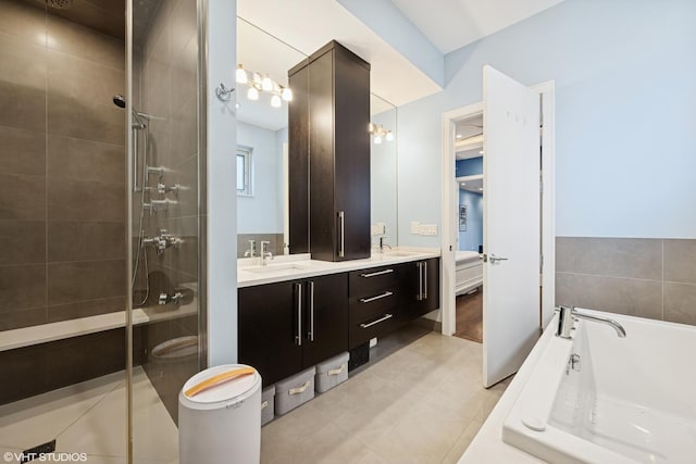 full bathroom featuring a stall shower, a bath, double vanity, and tile patterned floors