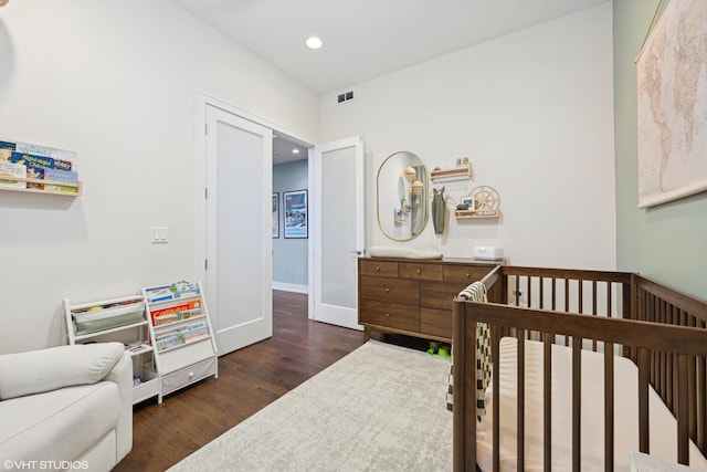 bedroom with a nursery area, wood finished floors, recessed lighting, and baseboards