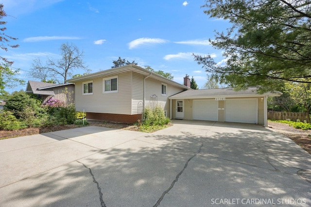 view of side of property featuring driveway, a garage, fence, and a chimney