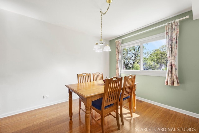 dining room featuring a chandelier, wood finished floors, and baseboards