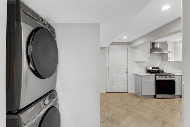 1315 S Kolin Ave, Chicago, IL 60623 - kitchen featuring stainless steel range with gas cooktop, wall chimney range hood, stacked washer and clothes dryer, light countertops, and tasteful backsplash