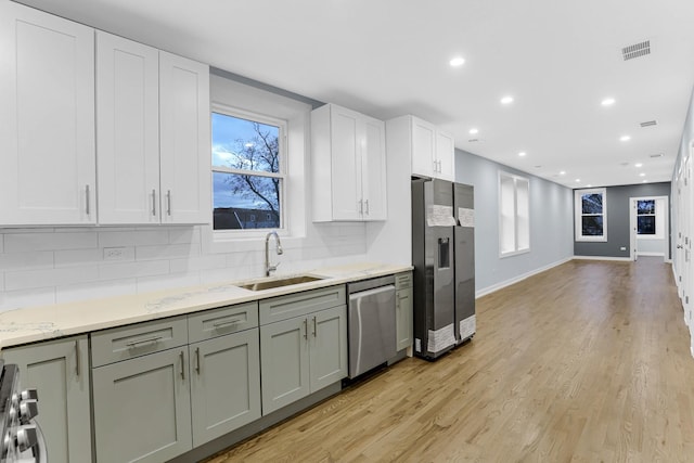 1315 S Kolin Ave, Chicago, IL 60623 - kitchen featuring appliances with stainless steel finishes, a sink, decorative backsplash, light wood finished floors, and recessed lighting