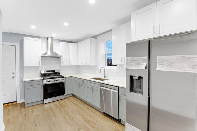 1315 S Kolin Ave, Chicago, IL 60623 - kitchen with stainless steel appliances, a sink, wall chimney range hood, gray cabinets, and light wood-style floors