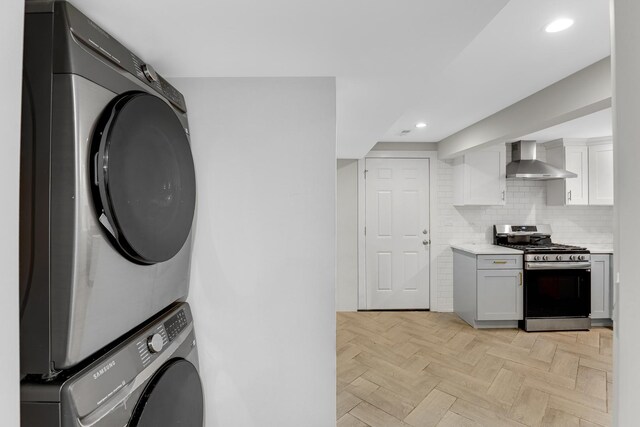 1315 S Kolin Ave, Chicago, IL 60623 - kitchen with gas stove, wall chimney range hood, stacked washer / dryer, light countertops, and white cabinetry