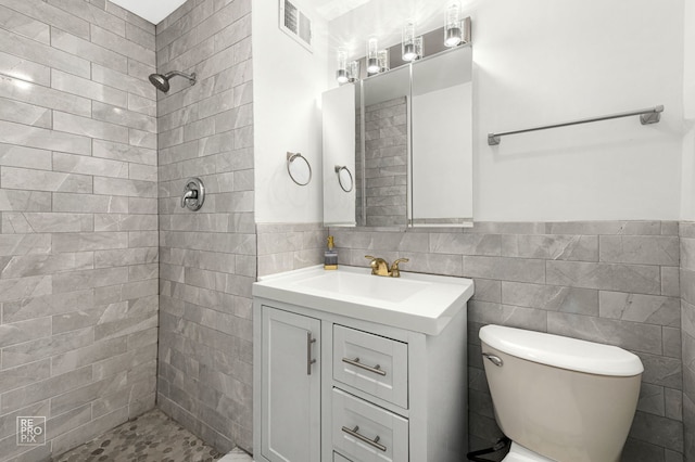 6301 N Sheridan Rd Unit 19O, Chicago, IL 60660 - bathroom featuring toilet, a tile shower, vanity, tile walls, and wainscoting