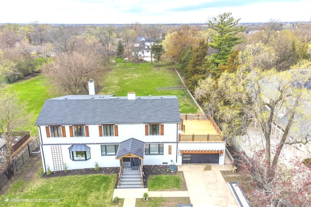 view of front of house with a shingled roof, concrete driveway, a chimney, and view of scattered trees